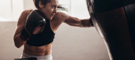 Woman is punching a boxing bag in a gym.