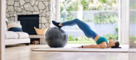 Woman doing an exercise on gym ball in a living room.